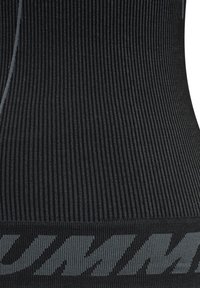 Svarta sportleggings med ribbad struktur, med en framträdande grå logoband. Tyget är elastiskt och formar sig efter kroppen.