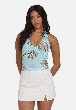 Hellblaues ärmelloses Oberteil mit V-Ausschnitt und braunem Blumenmuster. Kombiniert mit einem weißen Minirock mit seitlichem Schlitz.