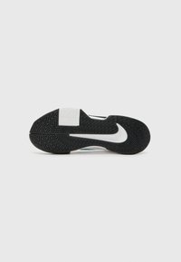 Svart gummisåle med fiskebensmønster og hvit Nike-logo, med delt design og teksturert overflate for godt grep.
