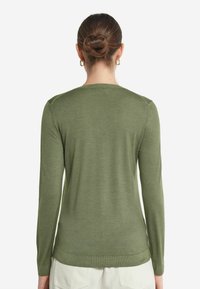 Långärmad tröja i olivgrön, med rund halsringning och ribbade muddar. Slät textur med minimal sömdetaljering vid axlarna.
