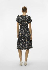 Robe noire fleurie à manches courtes avec une taille ceinturée, présentant une variété de pétales et de feuilles colorés sur un tissu léger.