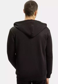 Czarna bluza z kapturem, wykonana z miękkiego, teksturowanego materiału. Posiada sznurki do regulacji, ściągacze przy rękawach oraz luźny krój, pokazana od tyłu.