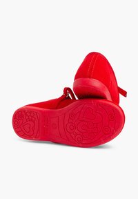 Pantofi din suede roșu, cu vârf rotund și curea la spate. Talpa din cauciuc prezintă modele embosate cu flori și inimi, sporind aderenta.