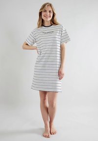 Camisón de algodón a rayas en blanco con líneas horizontales en azul marino. Mangas cortas, cuello redondo y un logotipo en el pecho. Diseño hasta la rodilla.