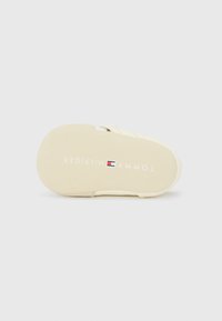 Sole delle sandali Tommy Hilfiger, in gomma beige con texture liscia, con logo bianco e rosso, forma rotonda, design minimal.