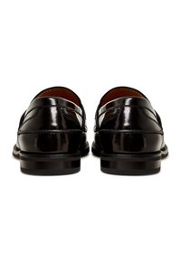 Paire de mocassins en cuir noir poli vus de dos sur un fond blanc.