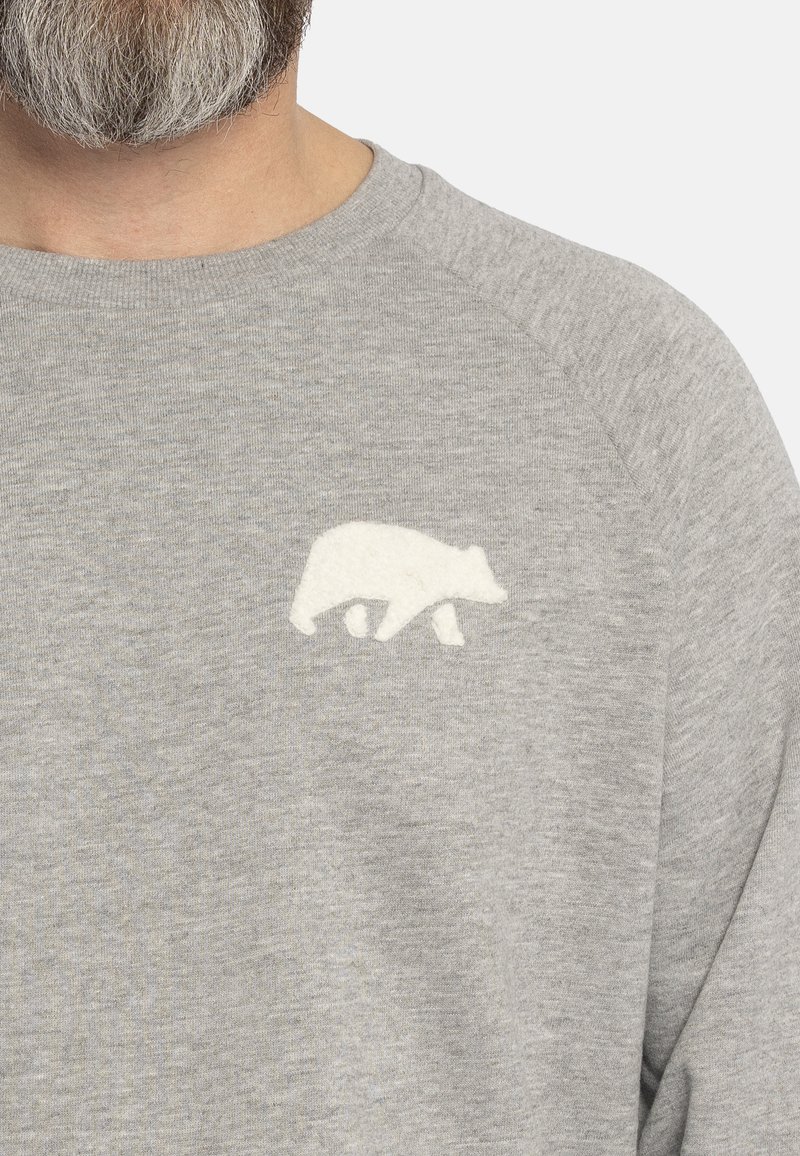 Grijze sweatshirt met een ronde hals en raglanmouwen. Heeft een witte vilt beren-silhouet op de borst. Zachte, jersey stof textuur.