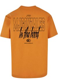 Orange bomulds T-shirt med korte ærmer, med sort tekst: "MJGONZALES" og "In tha hood" i fed skrift på ryggen.
