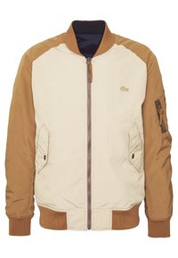 Veste bomber beige et marron zippée avec poignets et col côtelés, poches avant à rabat et petit logo brodé sur la poitrine.