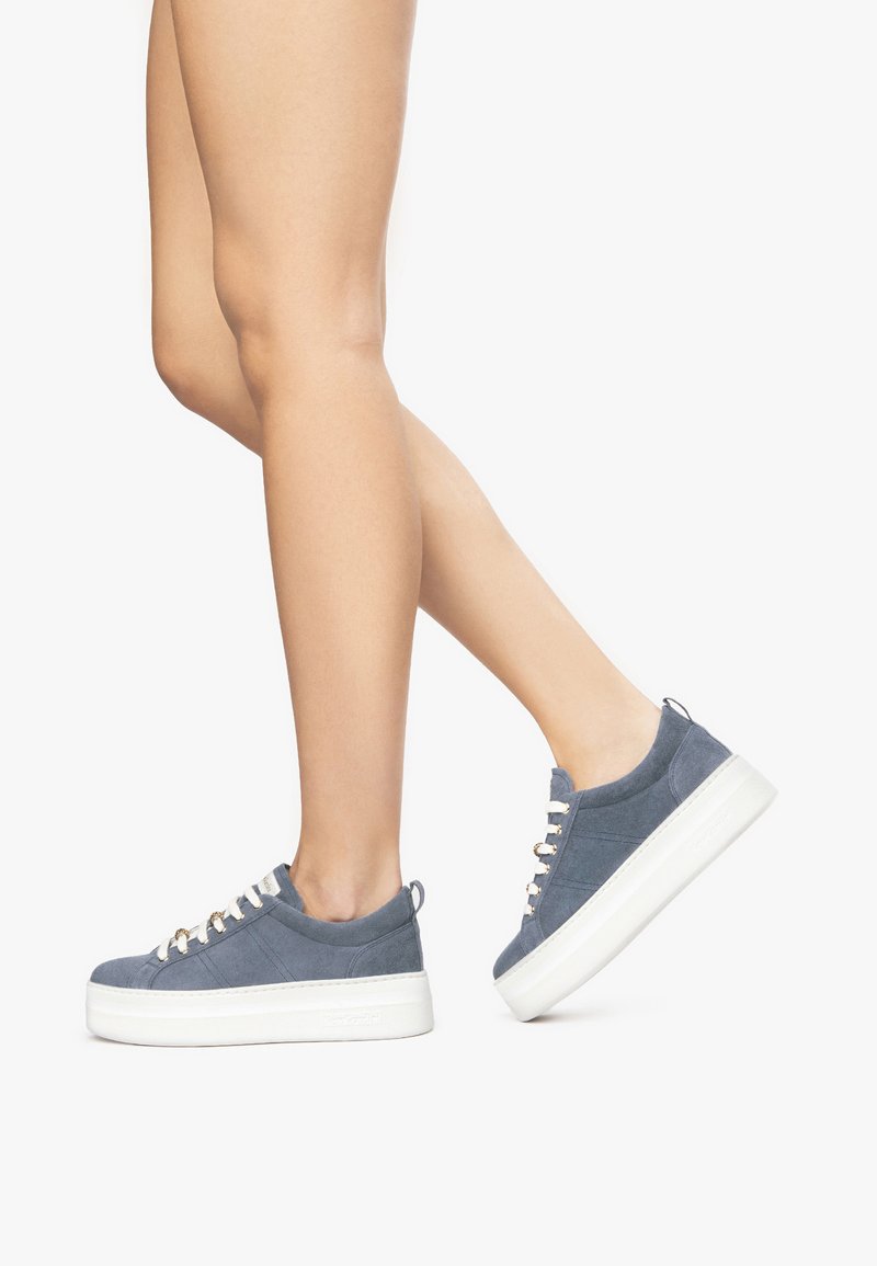 Baskets compensées en daim bleu avec semelles en caoutchouc blanches, dotées de lacets de couleur claire et de détails de design minimalistes.