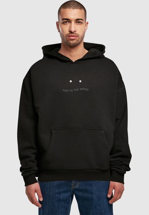 Black hooded sweatshirt with a front pocket, featuring the text "NOT IN THE MOOD" in white above two dots. Soft fabric with a relaxed fit.