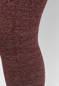 Bordeaux legginsy z teksturowanej powierzchni, z subtelnym metalicznym wzorem, dopasowany krój i gładkie wykończenie.