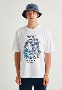 Camiseta de algodón blanca con un diseño gráfico marino en azul y negro que incluye texto. Mangas cortas y escote en cuello redondo.