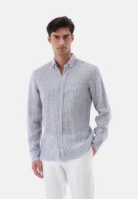 Camicia a righe blu e bianca, con colletto, maniche lunghe e taschino sul petto, realizzata in tessuto leggero.