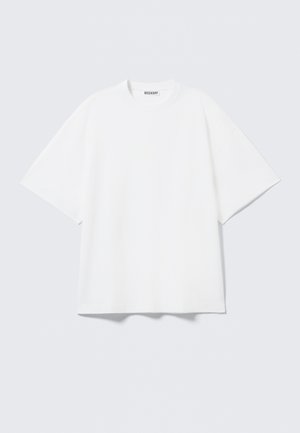 Hvit oversized t-skjorte laget av bomull. Har korte ermer, rund hals og subtile sømdetaljer. Merkevarelogo ved halsen.