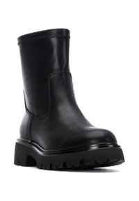 Botín de cuero negro hasta el tobillo con suela de goma gruesa, puntera redondeada y un diseño de costura minimalista alrededor del caña.