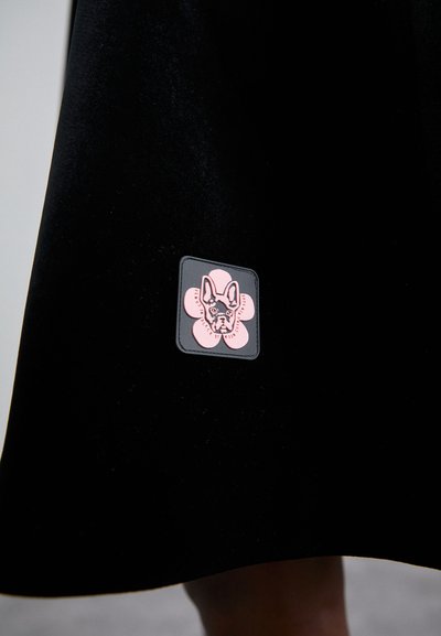 Black fabric skirt featuring a textured patch with a pink flower design and a French bulldog illustration in the center.