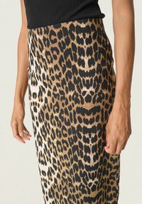 Jupe à motif léopard avec des teintes noires, beige et dorées ; fabriquée dans un tissu lisse. Présente une taille ajustée et une silhouette évasée.