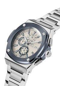 Silverfärgad klocka i rostfritt stål med en blå bezel, texturerad krämfärgad urtavla och tre underdials. Utrustad med applicerade timmarkörer och tryckknappar.
