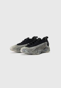 Une paire de baskets noires avec des semelles marbrées grises et des trous de ventilation sur les côtés, posées sur un fond blanc uni.