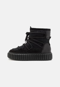 Svart høytopp sneaker med en blanding av teksturert stoff og semsket skinn i overdelen, tykk gummisåle og markante snøringer.