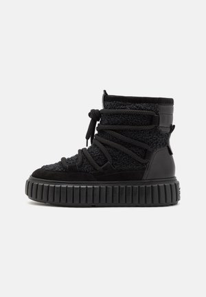 Sneaker alto nero con tomaia in materiali misti, tessuto testurizzato e suede, suola in gomma spessa e lacci prominenti.