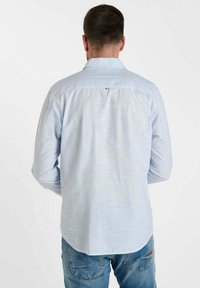 Lichtblauw overhemd met lange mouwen en dunne strepen, met een button-down kraag en een klein logo op de achterkant. Gecombineerd met blauwe denim jeans.