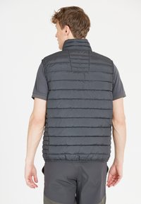 Leichter, grauer gesteppter Weste mit hohem Kragen und horizontaler Polsterung. Verfügt über einen elastischen Saum und eine glatte Textur. Wird über einem kurzärmeligen Hemd getragen.
