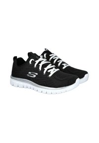 Zapatillas deportivas negras con parte superior de malla, cordones blancos y una suela acolchada blanca. Presentan un logotipo en el lateral y una lengüeta en el talón.