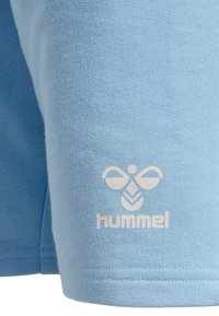 Jasnoniebieska bawełniana koszulka z fakturowanego materiału, z białym logo Hummel i wzorem pszczoły miodnej na lewym rękawie.