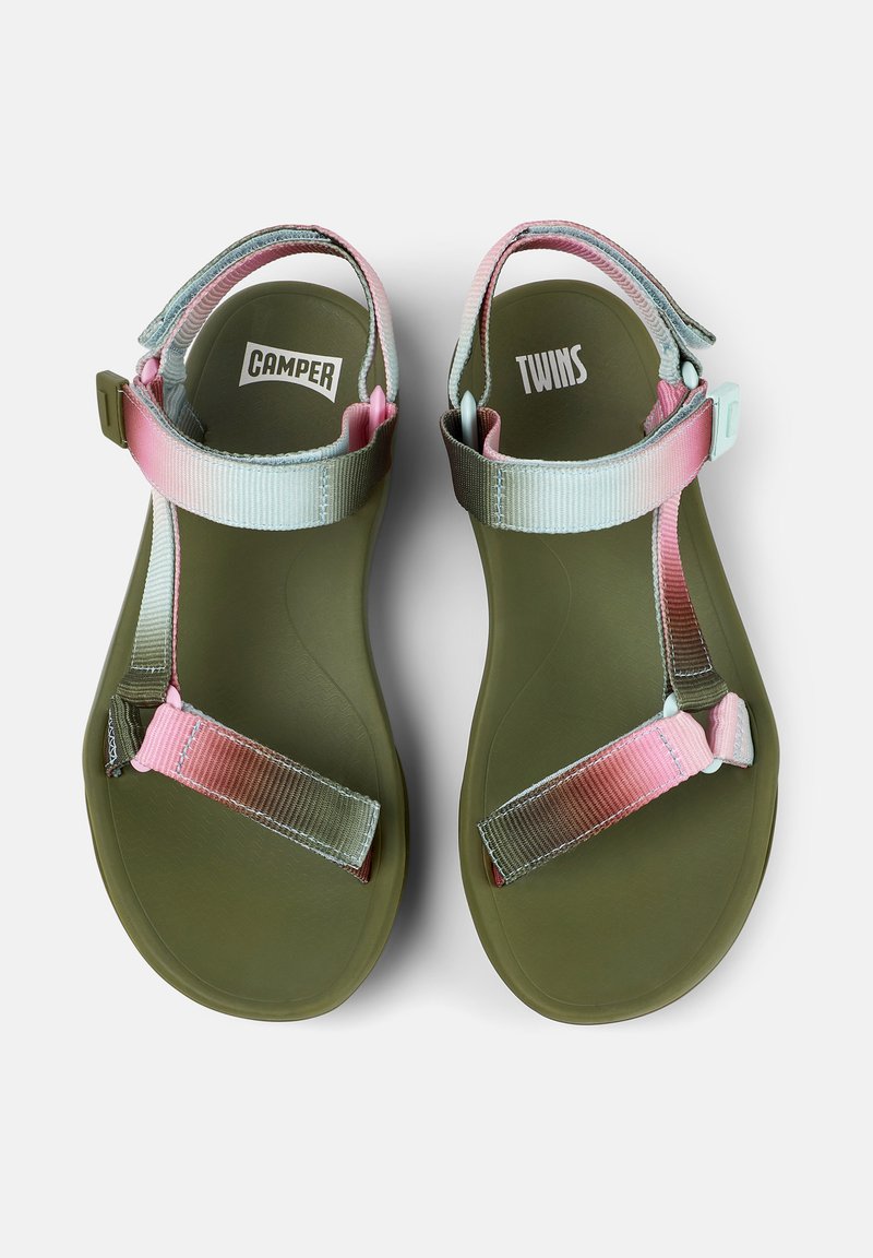 Un paio di sandali verde oliva con cinturini regolabili nei colori rosa pastello e blu, etichettati "Camper" sul piede sinistro e "Twins" sul piede destro.