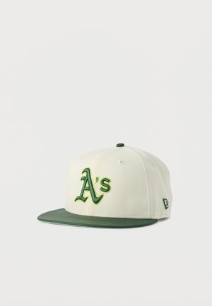 Hvit og grønn baseballcaps med en grønn "A's"-logo foran og en flat grønn brem mot en ensfarget hvit bakgrunn.