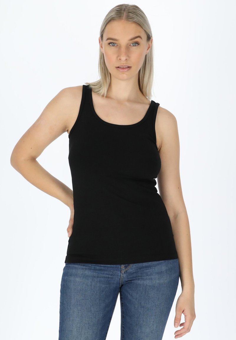 Top nero senza maniche con spalline larghe, realizzato in tessuto di cotone morbido. Design aderente, abbinato a jeans di denim blu, donna in posa con una mano sul fianco.