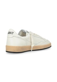 Baskets blanches en cuir avec une semelle en caoutchouc texturée crème. Présentent un bout arrondi, un laçage à l'avant et un branding subtil au niveau du talon.