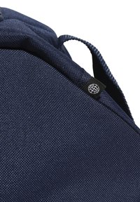 Marine tas van stof met textuur, gevoerd bovenwerk, verstelbare schouderbanden en een zwart label met een witte wereldbol logo.