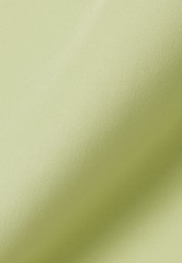 Tissu lisse de couleur vert pâle avec une texture finement tissée et des plis doux créant des ombres délicates.