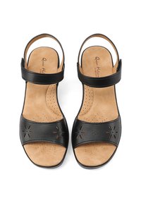 Sandali neri in pelle con cinturino alla caviglia, design floreale perforato sulla banda del dito e soletta imbottita color ocra. Suola piatta per il massimo comfort.