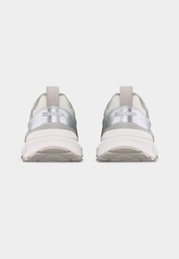 Paire de baskets blanches et argentées Calvin Klein vues de dos sur un fond clair uni.