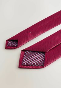 Texturiertes rotes Paar mit einem geometrischen Muster, das ein blaues und schwarzes gemustertes Futter aufweist. Verjüngte Enden und glattes Oberflächenmaterial.