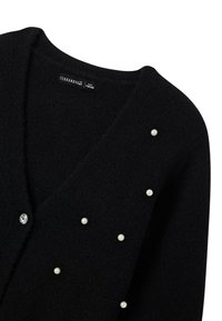 Czarny kardigan o miękkiej strukturze, z perłowymi akcentami i guzikiem z kamieniem szlachetnym. Projekt w serek z lekko luźnym krojem.