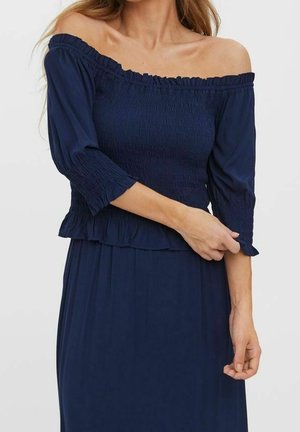 Navy off-the-shoulder top featuring three-quarter sleeves, smocked bodice, and ruffled hem. Soft fabric with a smooth texture.