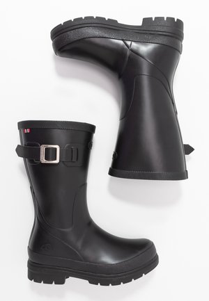 Para czarnych gumowych kaloszy do połowy łydki z regulowanymi srebrnymi paskami z klamrami i teksturowaną podeszwą na białym tle.