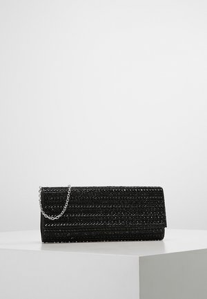 Pochette rectangulaire noire avec surface perlée texturée et courte chaîne argentée reposant sur une plateforme blanche sur fond uni.