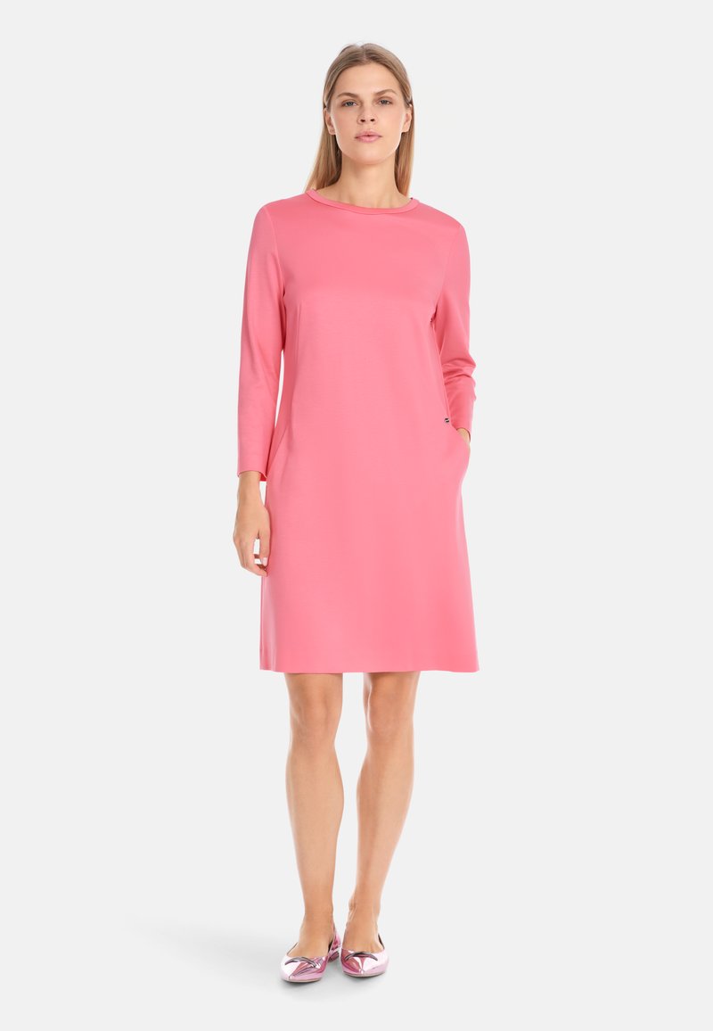 Roze jurk met lange mouwen, rond decolleté, een relaxte pasvorm en zijzakken. Van gladde stof en valt boven de knie.