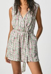 Květinový overal s výstřihem do V, bez rukávů a se stahovacím pasem. Obsahuje zelené a růžové květinové vzory na bílém pozadí.