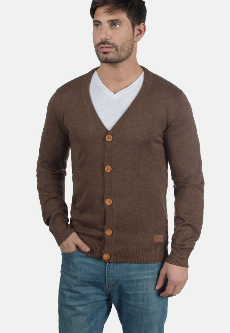 Cardigan in maglia marrone con scollatura a V, chiusura a bottoni e orlo a coste. Presenta cinque bottoni in legno ed è indossato sopra una maglietta bianca.