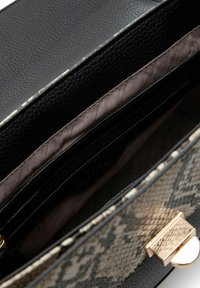 Schwarz mit Schlangenprägung gestaltete Handtasche mit einem goldfarbenen Verschluss, strukturiertem Lederaußenmaterial, geräumigem schwarzem Innenraum mit mehreren Fächern und glatter Fütterung.