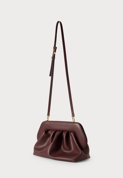 Sac à main en cuir bordeaux avec un design noué, de douces plis, un dessus plat et une longue bandoulière réglable avec des accents en métal doré.
