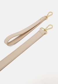 Bandoulières en cuir beige avec fermoirs en métal doré sur fond blanc, une bandoulière est bouclée et l'autre est à plat.