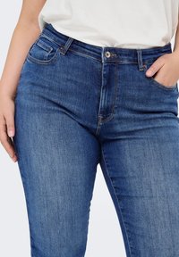 High-waisted blue denim jeans with a classic fit, featuring five pockets, stitching accents, and a smooth texture.